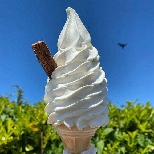 Ice cream cone with a waffle cone and chocolate stick against a blue sky