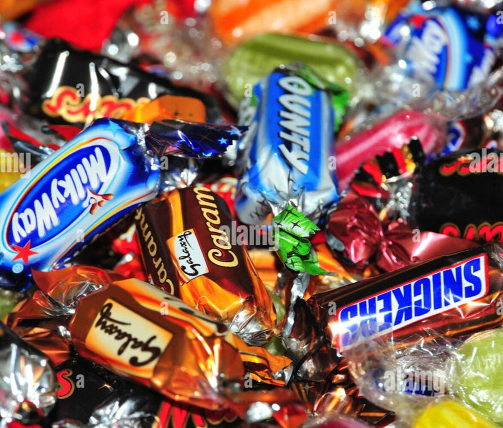 Assorted candy bars including Milky Way, Cadbury, and Snickers in colorful wrappers.